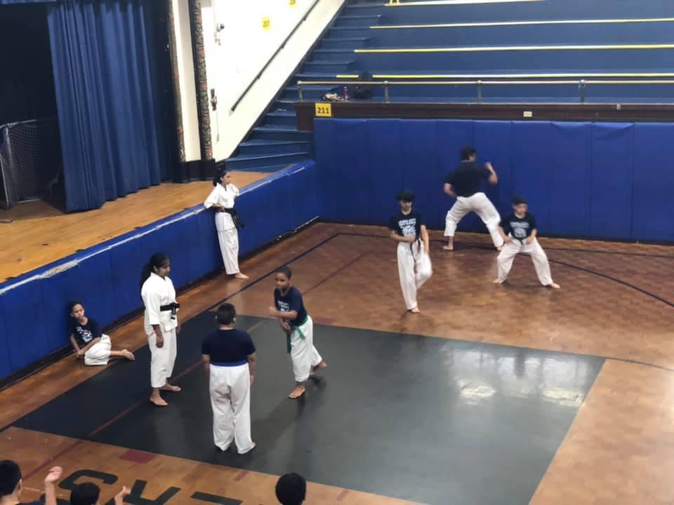 boys and girls in the gymnatorium practicing martial arts
