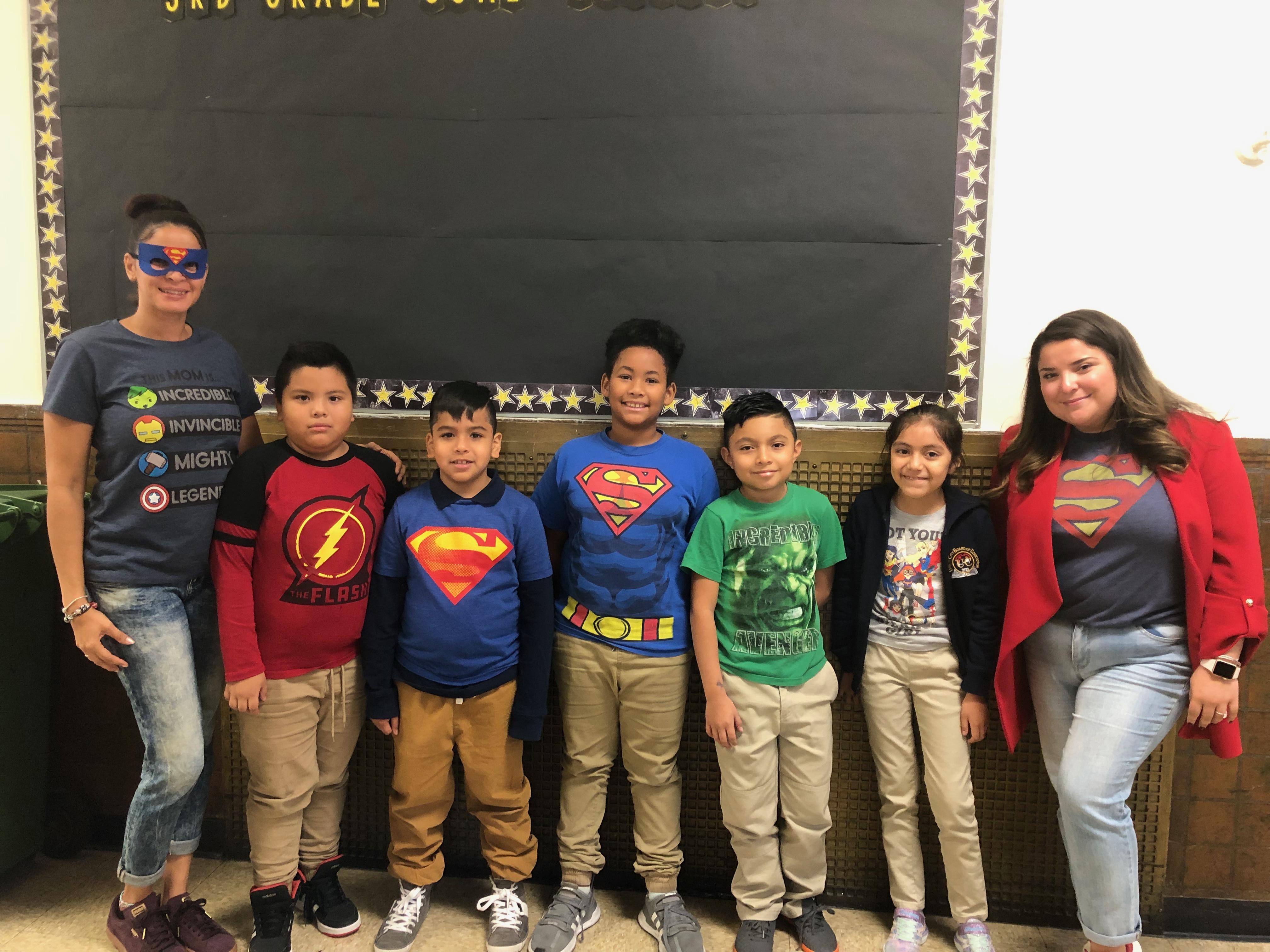 teacher with aide and several students wearing super hero t-shirts